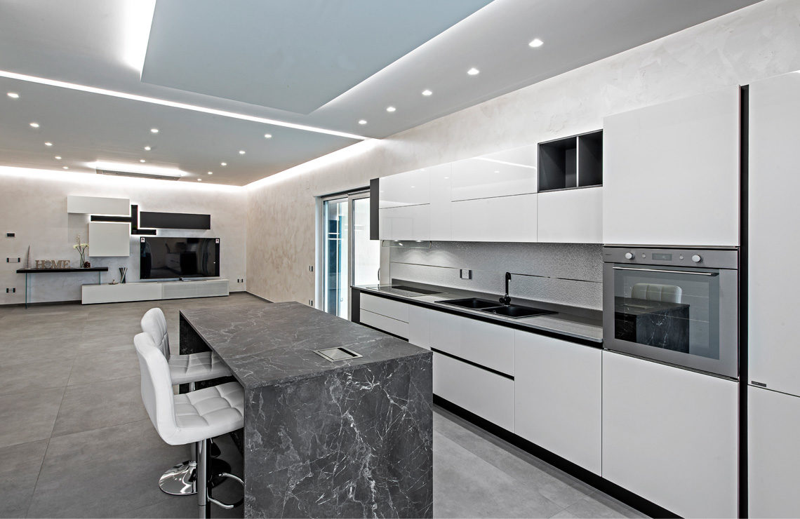 A casa di Elvira e Giuseppe: una cucina con isola effetto marmo e bianco coordinata alla zona giorno. Progetto CasaStore Arredamenti Salerno.